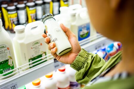 BANGKOK THAILAND - January 12, 2020: Woman's hand buying milk in the supermarket. Woman choosing...