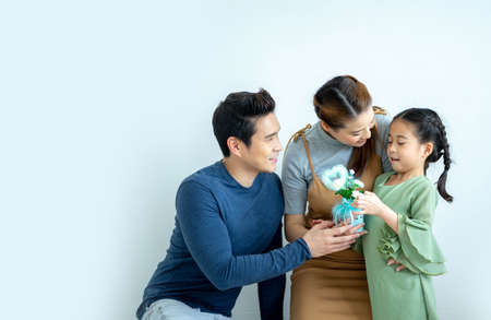 Asian Family child daughter congratulates mom and gives her flowers. Mother's day celebration in family.の写真素材