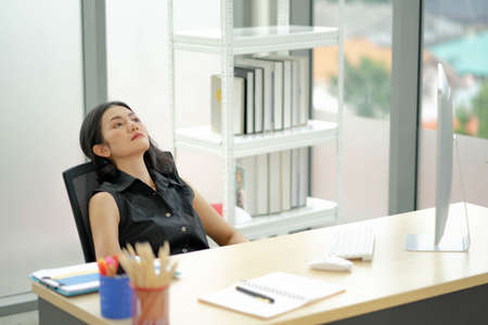 Distracted from work worried asian woman sitting on couch with laptop, thinking of problems. Pensive unmotivated lady looking at laptop, feeling lack of energy tasks at office.の写真素材