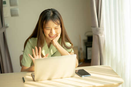 Asian young woman use laptop computer and video call with friend in home, work from home.