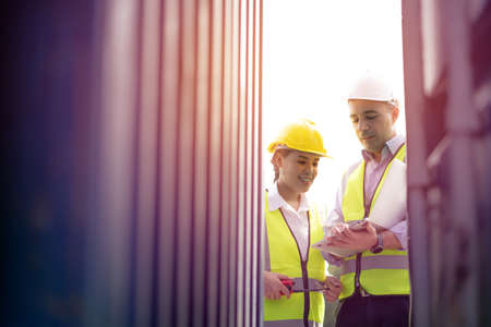 Two logistic staff checking and control loading containers box from cargo. transportation import,...