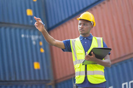 American African Engineer or supervisor checking and control loading Containers box from Cargo at...
