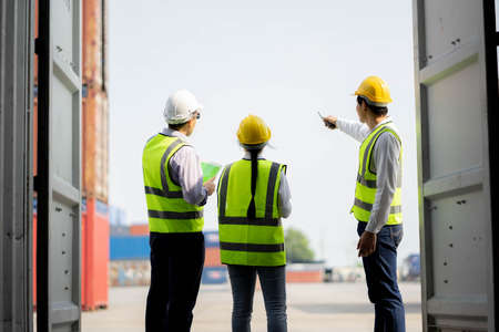 Team engineer dock control logistics worker wear safety helmets and protect suite open cargo...