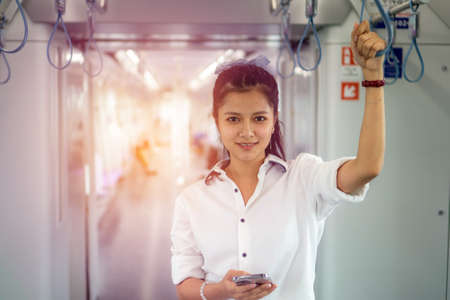 Young Asian Woman using mobile phone in sky train car, leisure and daily life.