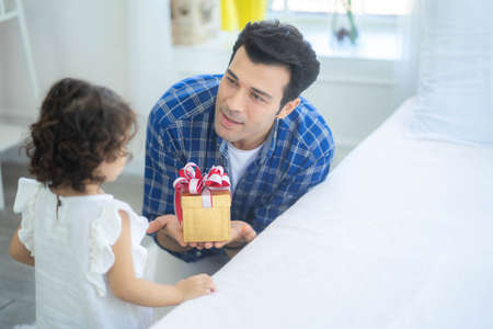 Handsome young father is giving a gift box to his cute little daughter, Love family day parenthood...