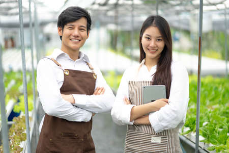 Hydroponics: new generation young Asian farmer couple smiles at the quality of organic vegetables harvested on the farm Commercially grown organic farming business ideaの写真素材