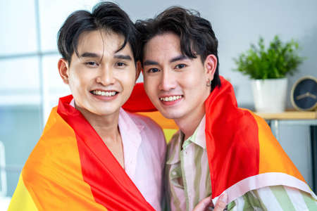 Gay Couple Embracing with Rainbow Flag.の写真素材
