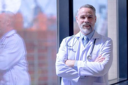 Confident smiling doctor posing and looking at camera with arms crossed.の写真素材