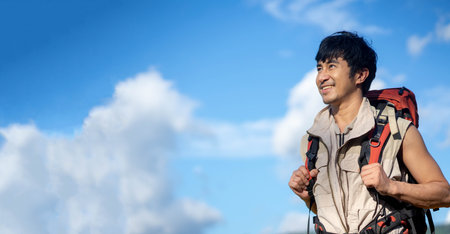 Young Asian man Smiling wanderer with backpack walking outdoors in nature, Travelers enjoy relaxing time in nature with copy space.の写真素材
