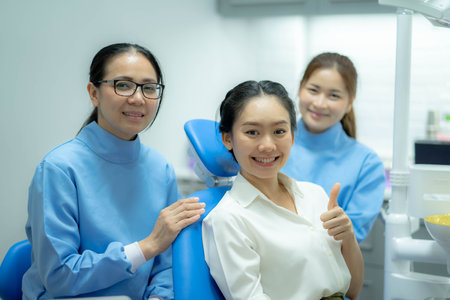 Portrait of girl patient smile, sitting on dental chair after doctor and assistant provide medical service. Young woman feel happy for oral care treatment services from professional dentist.の写真素材
