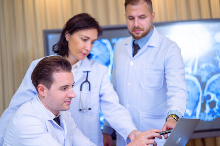 Team of doctors discusses the results of an MRI scan of the patient's head in the consulting room of modern hospitalの写真素材