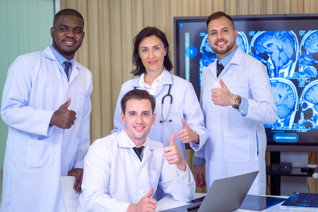Group Of Happy multicultural doctors showing thumbs up and smiling on camera while posing at conference room. Portrait of multiracial medical specialists in white lab coats.の写真素材