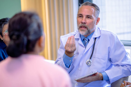 Doctor consulting senior old patient. doctor talking to a patient group in the officeの写真素材