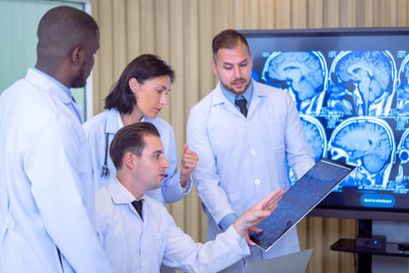 Team of doctors discusses the results of an MRI scan of the patient's head in the consulting room of modern hospitalの写真素材