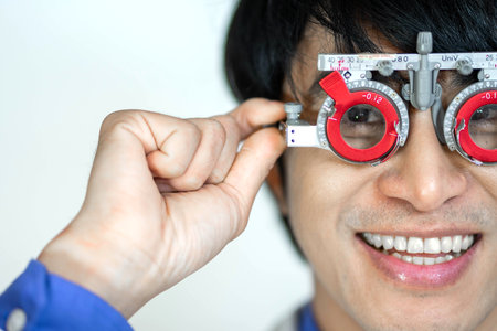 Happy man checking vision with eye test glasses during a medical examination at the ophthalmological office, Checking eye vision by optician health examination conceptの写真素材
