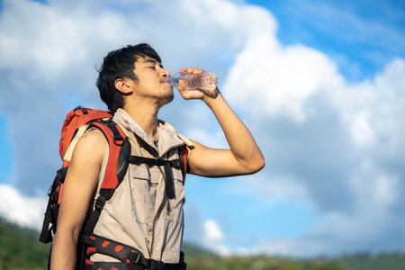 Backpacker Asian men drink bottled water. The young man lives an enthusiastic life.の写真素材