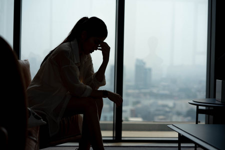 silhouette of a young woman sitting on a sofa spending time alone at home, young upset pensive woman feeling lonely or frustrated thinking about problems, The concept of depression.の写真素材