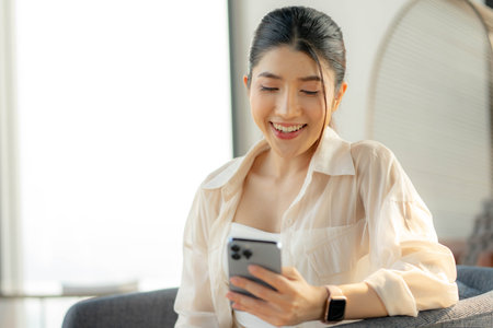 happy woman checking social networks on smartphone, Young lady with mobile device browsing web, Weekend at home.の写真素材