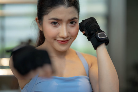 Beautiful young woman wearing boxing gloves posing in combat stance looking at camera. Workout in a Gym.の写真素材