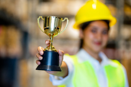 warehouse Staff Happy holding a trophy after being selected as an outstanding employeeの写真素材