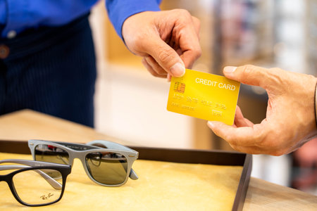 Man pays with credit card for the new glasses. Consumerism and modern technology. Payment methodの写真素材
