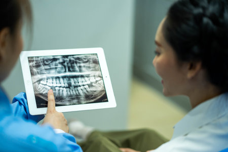 female dentist shows the patient his x-ray, the x-ray is explains the procedure and treatment he...