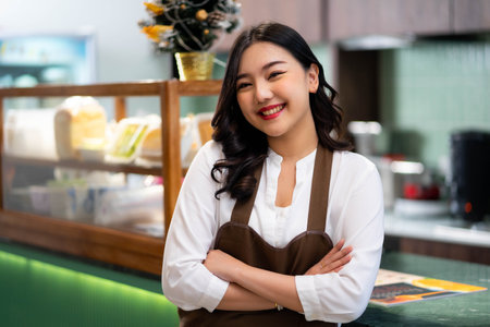 Smiling young asian waitress wearing an apron and smiling while standing in a restaurantの写真素材