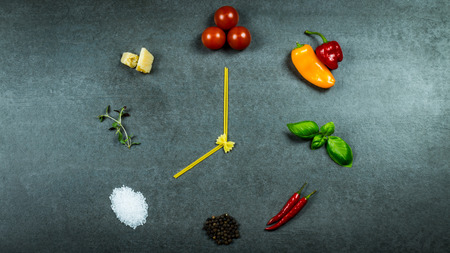 Clock out of pasta, tomatoes, peppers, basil, chili, pepper, sea salt, thyme and parmesan on dark...