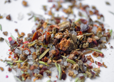 many different spices and large salt scattered on a white background
