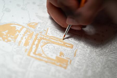 Girl hand draws with a brush painting by numbers on canvas. Creative hobby during the quarantine. Picture by numbers. Drawing on canvas. Closeup, selective focusの写真素材