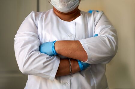 the girl in the medical gloves and lab coat crossed her arms over her chest.の写真素材