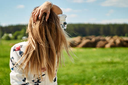 back figure woman touches her loose hair from behind.の写真素材