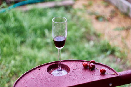a glass of red wine and a cherry on the background of the gardenの写真素材