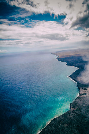 Aerial view of volcanic landscape with turquoise sea and clouds Hawaii