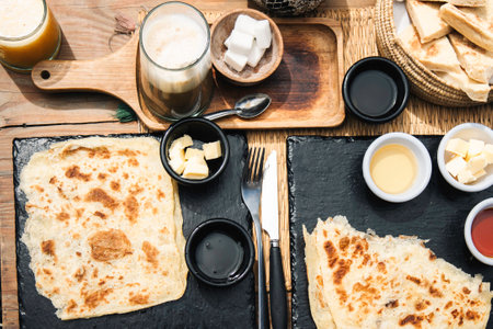 Delicious traditional Moroccan breakfast in essaouira with flatbread, fermented butter, local honey, amlou and nos nos coffee top view of rustic setting with condiments on rustic black slate platesの写真素材