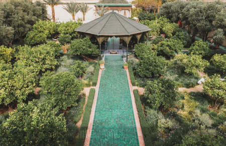 Lush garden path with green tiles and green plants at Le Jardin Secret Marrakech, symmetrical traditional Moroccan design, serene, luxury elegant outdoor settingのeditorial素材