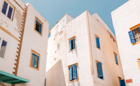 Traditional whitewashed buildings with iconic vibrant blue shutters in essaouira medina under a clear sky, Moroccan architecture and design elements in picturesque North African coastal town, Moroccoのeditorial素材