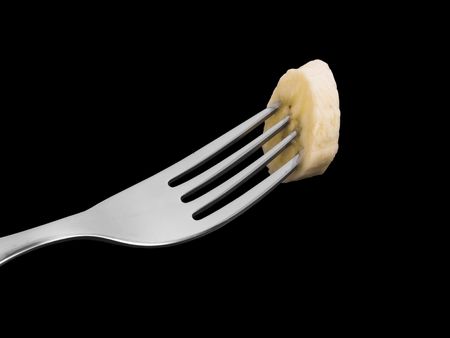 Banana slice on a fork with black backgroundの写真素材
