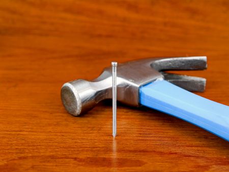 Hammer and nail on a wooden background