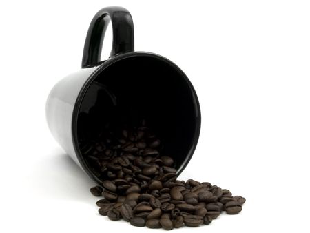 black mug spilling coffee beans on a white backgroundの写真素材