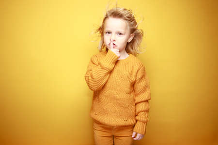 little girl smiling in front of a yellow backgroundの写真素材