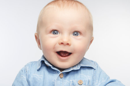 The innocent face of a little baby expresses such a joyful and charming air under the light of a studio.の写真素材