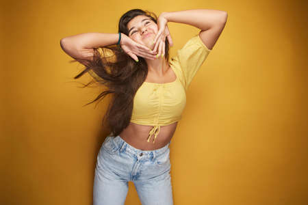 A girl expressing various emotions on her face under the yellow color, expression in the eyes, laughter with white teeth, grimace, joy of life and full of energy on her body.の写真素材