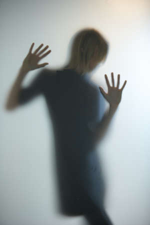 Image of a woman blurred behind a glass with sexy postures and well framed to give meaning to the photo as what, even without detail of a face, a photo can still express some things.の写真素材