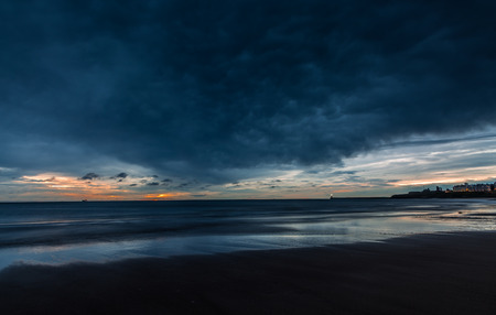 A cloudy start to the day at Tynemouth Longsands as the sun rises on the horizonの写真素材