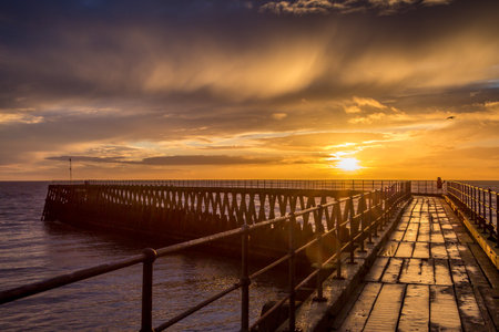 A glorious morning at Blyth beach, with a beautiful sunrise over the old wooden Pier stretching out to the North Seaの写真素材