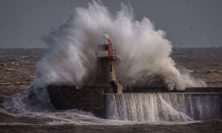 Giant waves batter the 15metre tall lighthouse which guards the south pier at the mouth of the Tyne at South Shields, Englandの写真素材