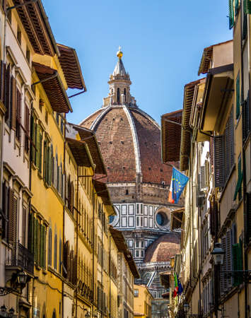 Looking along a street with shutters and flags, towards the Duomo in Florence, Italy.の写真素材