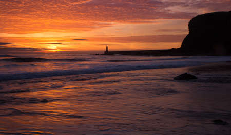 A beautiful sunrise at Tynemouth's King Edward's Bay, as the sky explodes with colorの写真素材