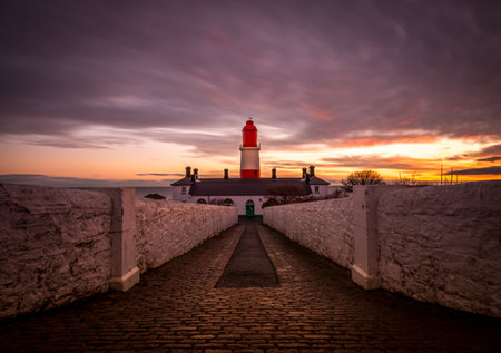 The pathway to the red and white striped, 23 meter tall,  Souter Lighthouse in Marsden, South Shields as the sun risesの写真素材